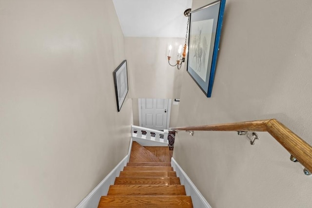 stairs with an inviting chandelier and baseboards