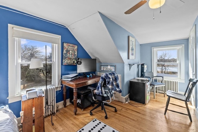 office space with vaulted ceiling, radiator heating unit, wood finished floors, and baseboards