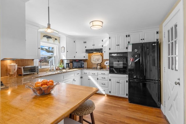 kitchen featuring white cabinets, a sink, under cabinet range hood, and black appliances