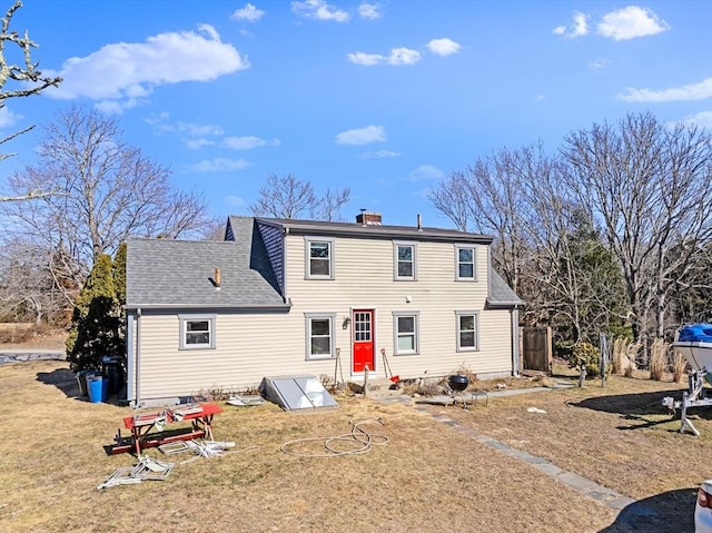 back of house featuring entry steps, a shingled roof, and a chimney