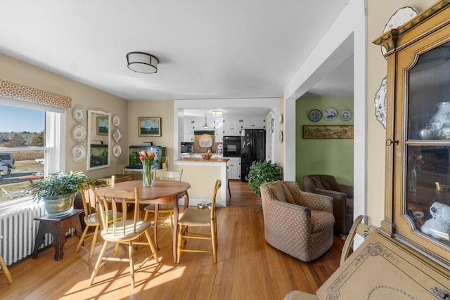 dining space with light wood-style floors and radiator