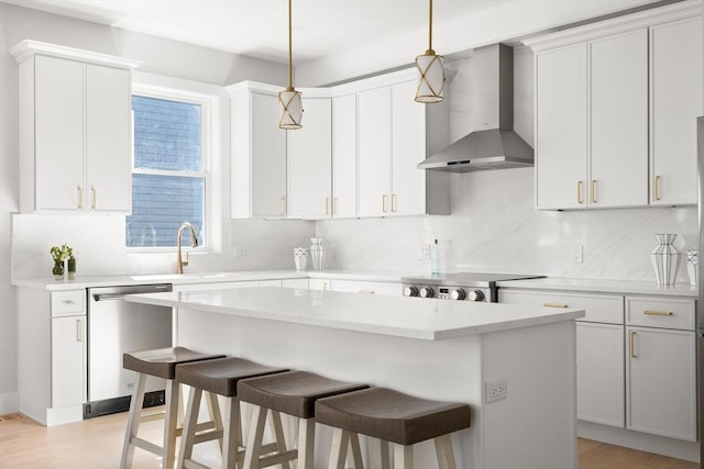 kitchen with wall chimney range hood, dishwasher, a kitchen breakfast bar, a center island, and decorative backsplash