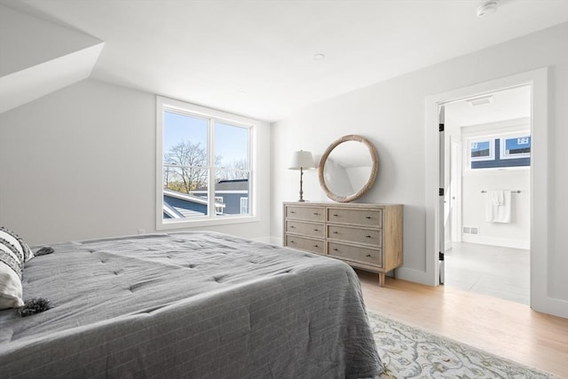 bedroom featuring multiple windows, light wood-style flooring, and lofted ceiling
