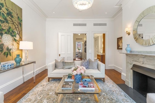 living room with a high end fireplace, wood finished floors, baseboards, and ornamental molding