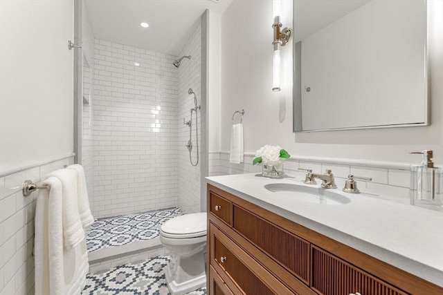 full bath with vanity, tile walls, toilet, and a tile shower