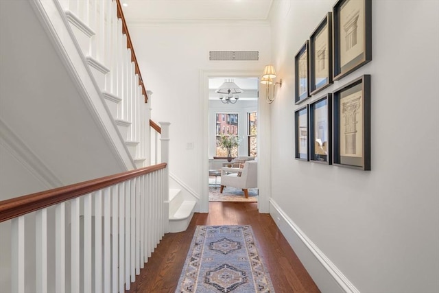 hallway featuring visible vents, wood finished floors, crown molding, baseboards, and stairs