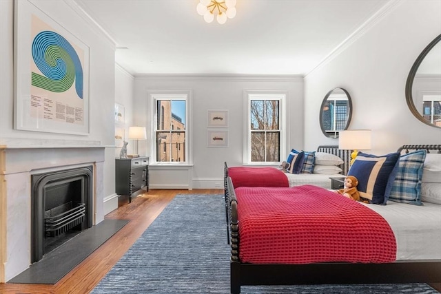 bedroom featuring wood finished floors, crown molding, a fireplace, and baseboards