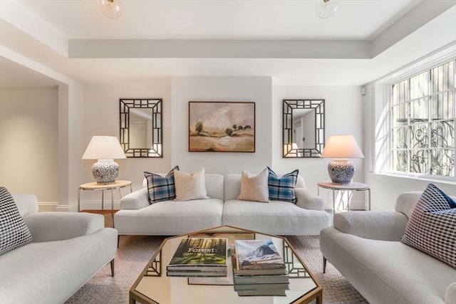 living room with a tray ceiling, baseboards, and wood finished floors