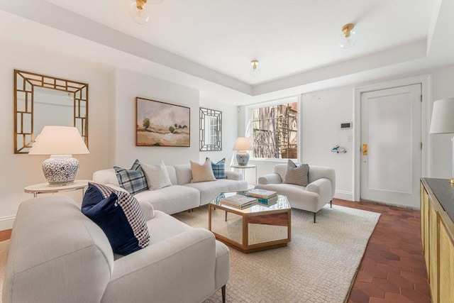 living area with a raised ceiling and baseboards