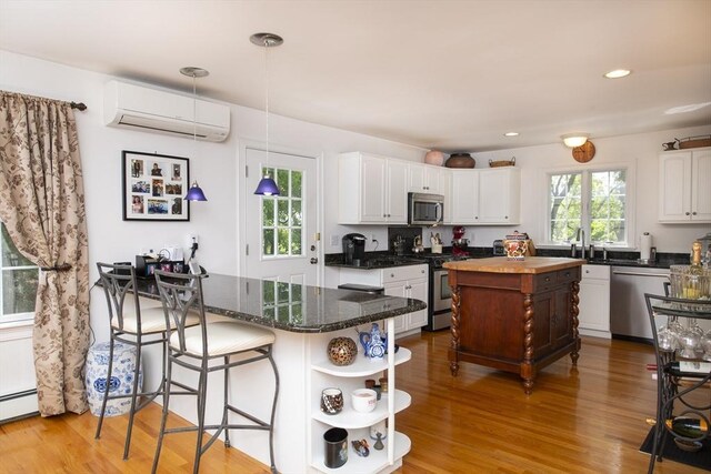 2181 Service Rd, Barnstable, MA 02668 - kitchen with appliances with stainless steel finishes, a wall unit AC, open shelves, white cabinets, and light wood-style floors