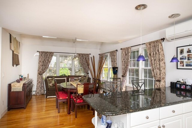 2181 Service Rd, Barnstable, MA 02668 - kitchen featuring a wall unit AC, light wood-style flooring, white cabinets, dark stone counters, and baseboards