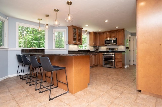 3 Eileen Rd, Norton, MA 02766 - kitchen featuring stainless steel appliances, brown cabinetry, a kitchen breakfast bar, glass insert cabinets, and recessed lighting