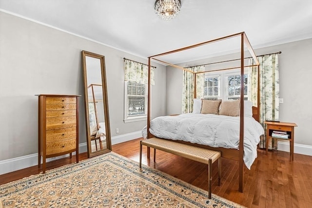 bedroom featuring an inviting chandelier, baseboards, and wood finished floors