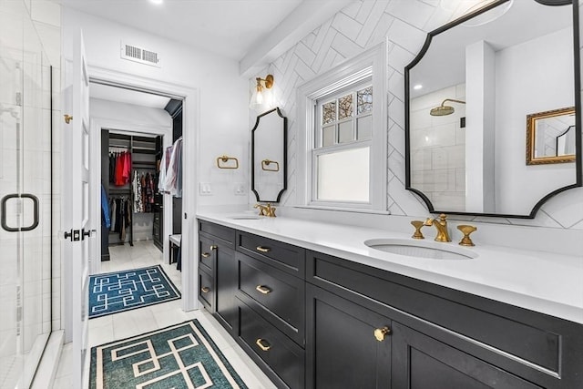 bathroom featuring a walk in closet, visible vents, a sink, and a shower stall