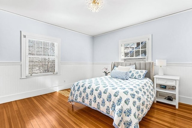 bedroom with a wainscoted wall and wood finished floors