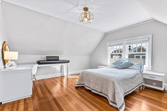 bedroom with vaulted ceiling, wood finished floors, and baseboards