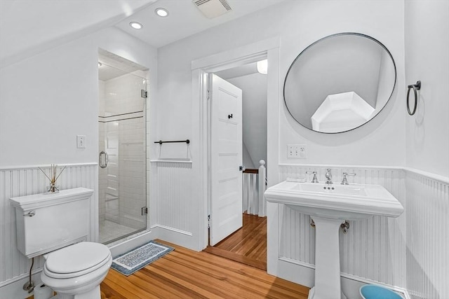 bathroom with toilet, wood finished floors, visible vents, wainscoting, and a stall shower