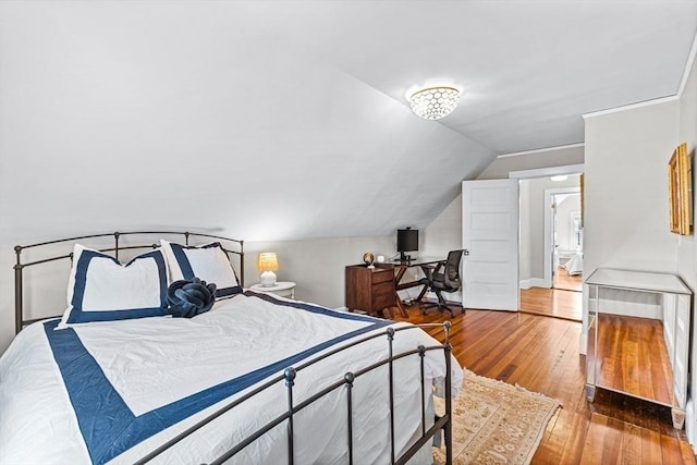 bedroom featuring lofted ceiling, baseboards, and wood finished floors