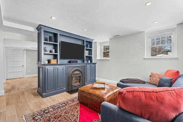 living room with light wood-type flooring, a healthy amount of sunlight, visible vents, and recessed lighting