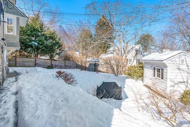 yard covered in snow featuring a fenced backyard, an outdoor structure, and a shed