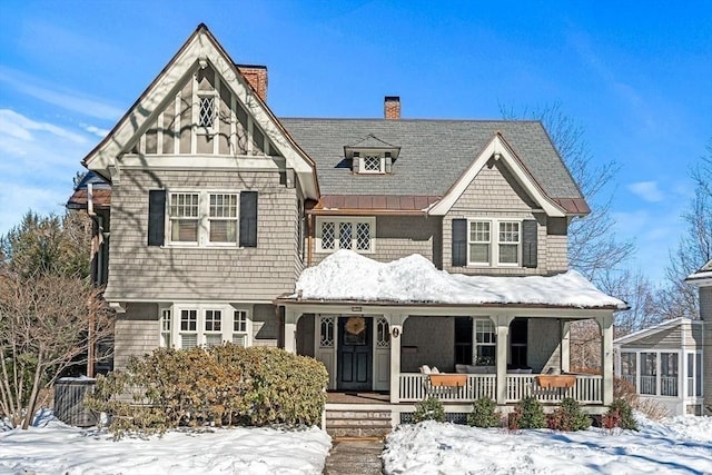 view of front of home with covered porch, a chimney, metal roof, and a standing seam roof