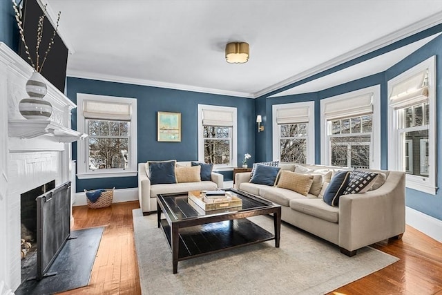 living room featuring a high end fireplace, crown molding, baseboards, and wood finished floors