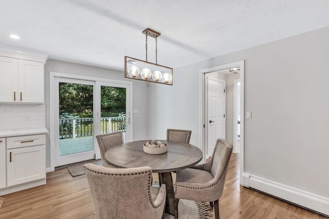 dining room with an inviting chandelier, light hardwood / wood-style flooring, and a baseboard heating unit