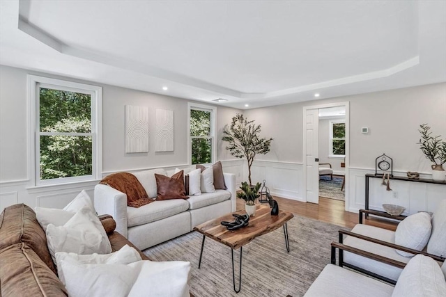 living room featuring hardwood / wood-style floors, a tray ceiling, and plenty of natural light