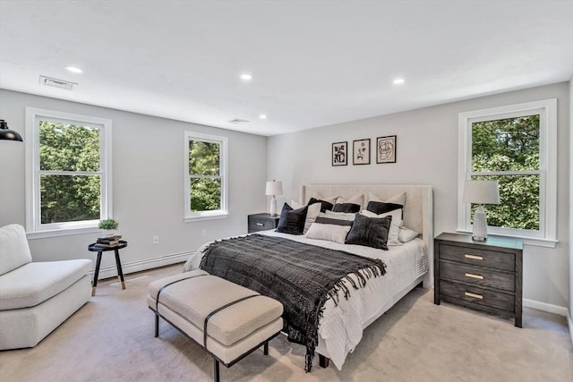 bedroom featuring multiple windows, light carpet, and a baseboard heating unit