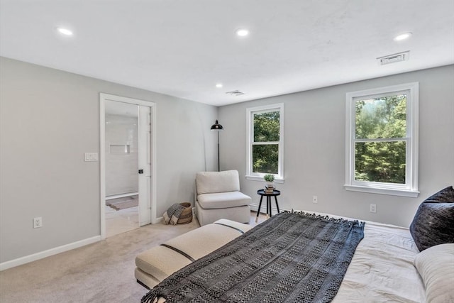 bedroom with baseboard heating, ensuite bath, and light carpet