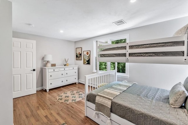 bedroom with light hardwood / wood-style floors and a baseboard radiator