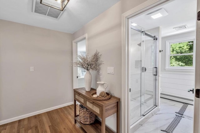 bathroom with hardwood / wood-style floors, a shower with door, and baseboard heating