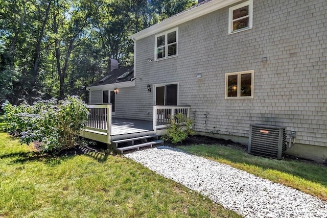 rear view of property with a lawn, central air condition unit, and a wooden deck