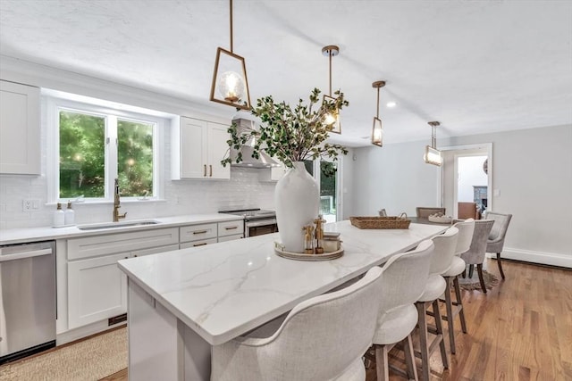 kitchen with pendant lighting, a center island, sink, appliances with stainless steel finishes, and white cabinetry