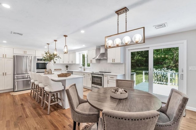 dining room with a wealth of natural light, sink, light hardwood / wood-style floors, and an inviting chandelier