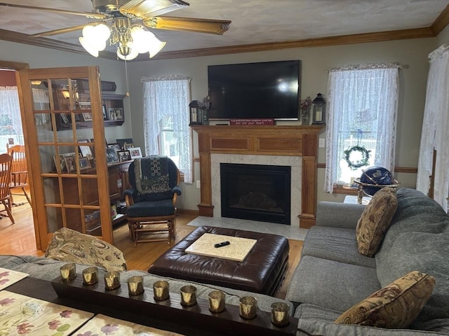 living area with crown molding, ceiling fan, wood finished floors, and a fireplace