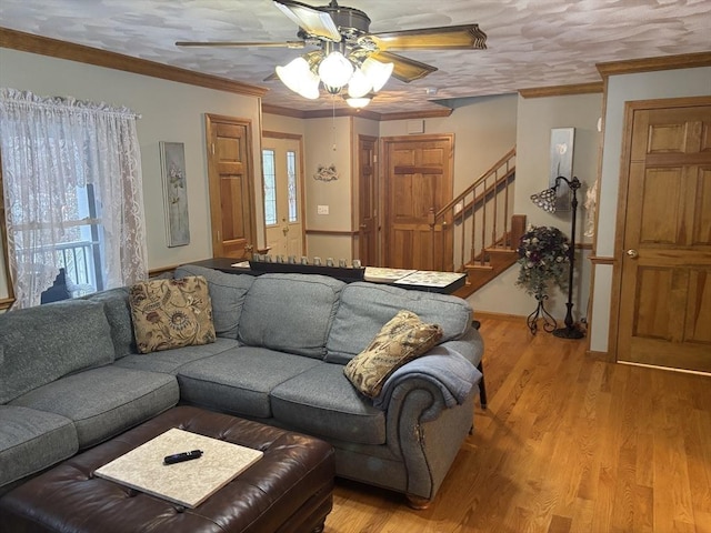 living area featuring stairs, ceiling fan, crown molding, and light wood-style flooring