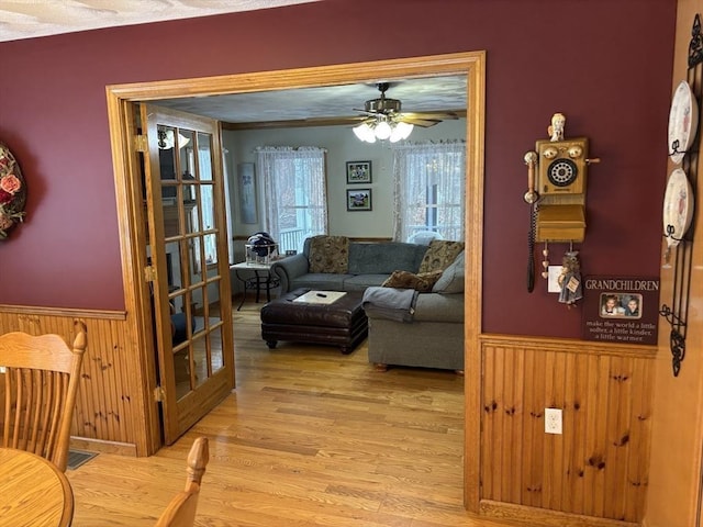 interior space featuring a ceiling fan, wainscoting, and light wood-type flooring