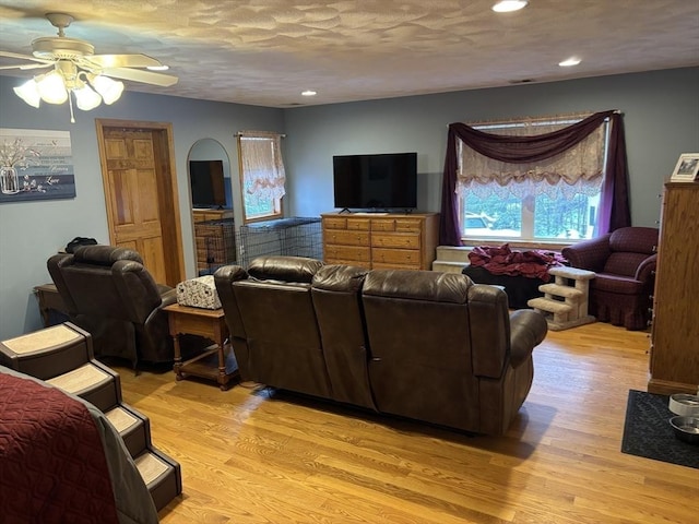 living area with light wood-type flooring, a ceiling fan, arched walkways, and recessed lighting