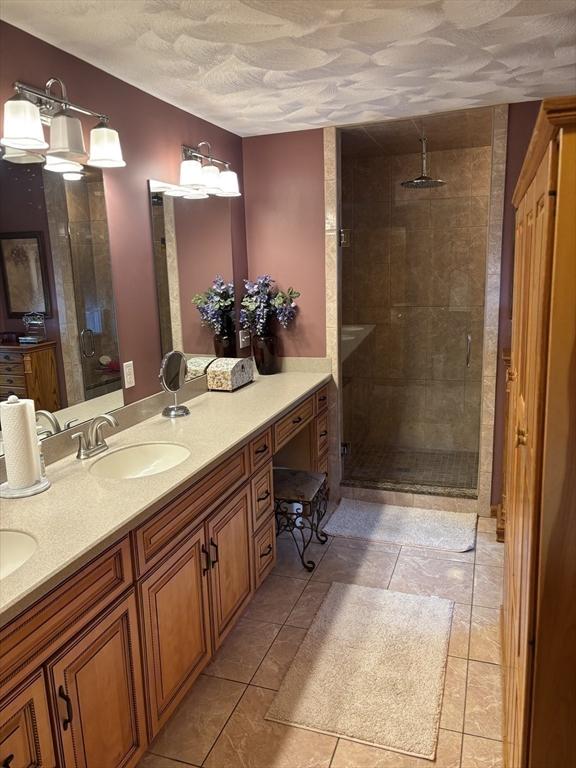 bathroom featuring a sink, a stall shower, and double vanity