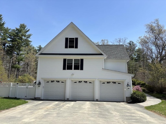 view of property exterior featuring concrete driveway, an attached garage, and fence