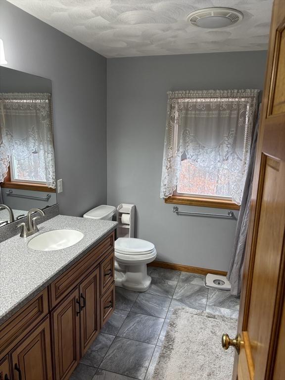 bathroom with vanity, baseboards, and toilet