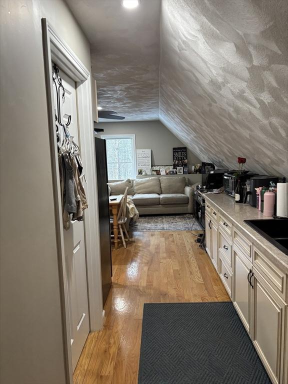 interior space with a sink, light wood-style flooring, and lofted ceiling