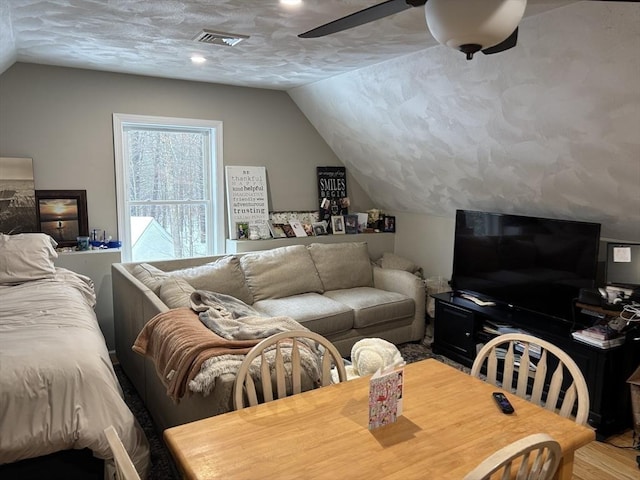 living room featuring vaulted ceiling, wood finished floors, and visible vents