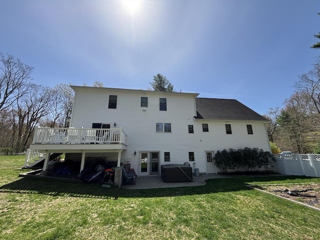 rear view of house featuring a wooden deck, a patio, a lawn, a hot tub, and stairway
