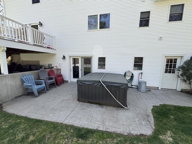 back of property featuring a hot tub and a patio area