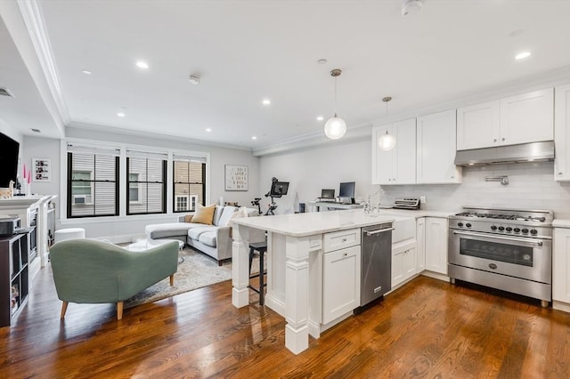 kitchen featuring appliances with stainless steel finishes, dark hardwood / wood-style floors, white cabinets, a kitchen breakfast bar, and kitchen peninsula