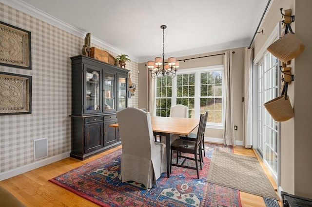 dining area featuring baseboards, wallpapered walls, light wood-style flooring, crown molding, and a chandelier