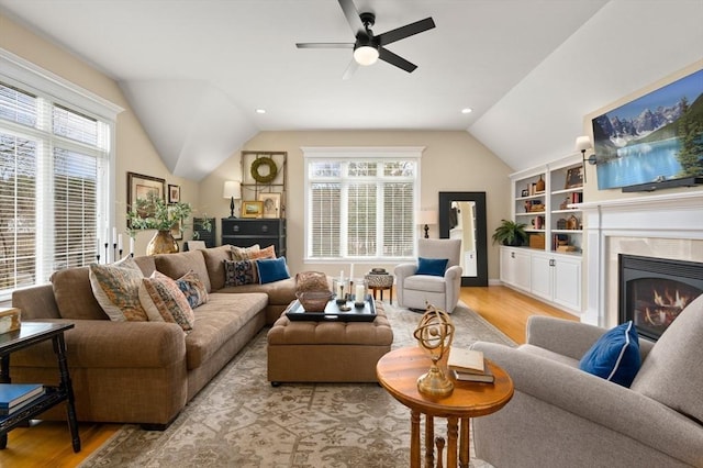 living room featuring lofted ceiling, a ceiling fan, wood finished floors, and a fireplace