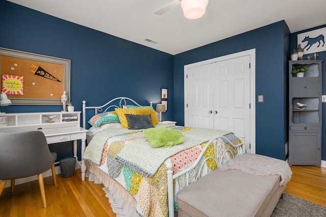 bedroom featuring ceiling fan, visible vents, a closet, and wood finished floors